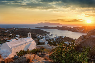 Aerial view of mountains by sea against cloudy sky during sunset