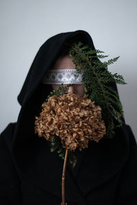 Close-up of woman with flowering plant against white background