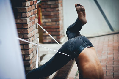 Low section of shirtless man performing stunt against column