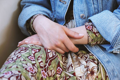 Mid section of young woman wearing denim jacket over summer dress with floral pattern