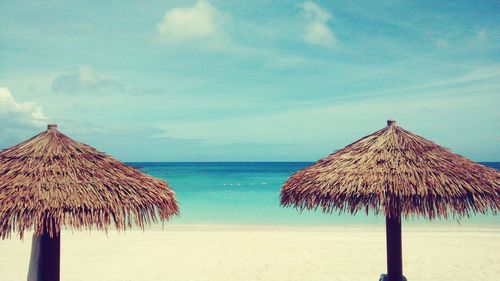 Thatched roof on beach against sky