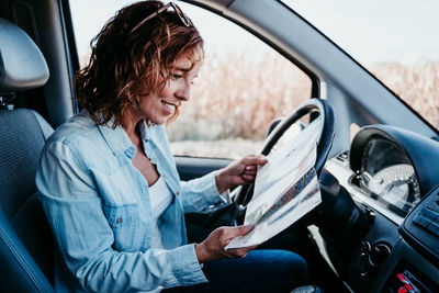 Side view of woman analyzing map in camper trailer