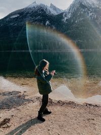 Side view of woman photographing by lake