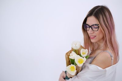 Portrait of young woman holding rose against white background