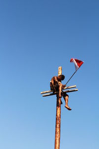 Low angle view of flags against clear blue sky