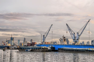 Cranes at commercial dock against sky