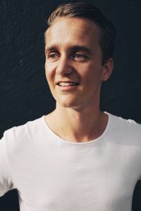 Portrait of young man standing against black background