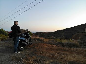 Man riding motorcycle on road against sky