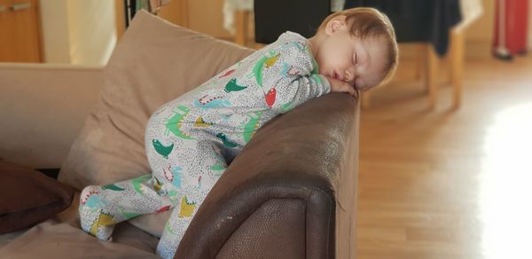 Cute baby boy sleeping on sofa at home