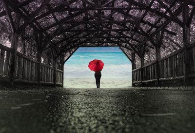 Covered walkway leading towards woman standing at beach