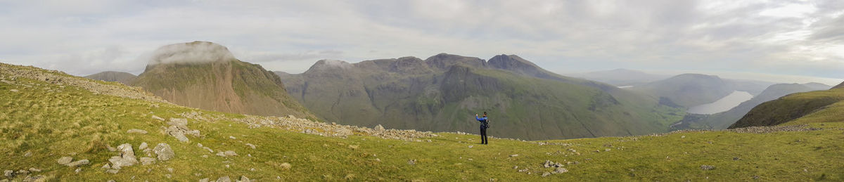 Rear view of man standing on mountain against sky