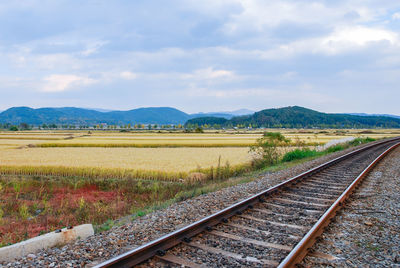 Railroad track by mountain against sky