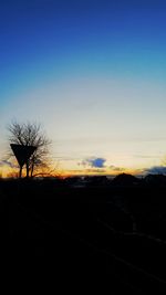 Bare trees on landscape at sunset