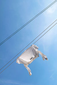 White shirt drying on clothesline at blue sky background. laundry concept.