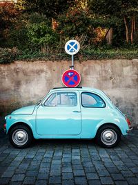 Vintage car parked under no parking sign on cobbled street