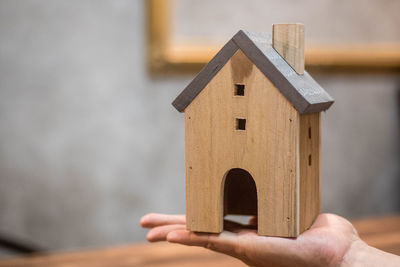 Close-up of hand holding birdhouse against building