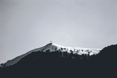 Silhouette cross on mountain against clear sky