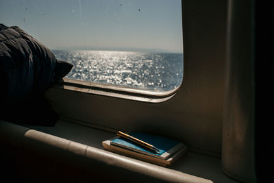 Close-up of books with pen by window in ship