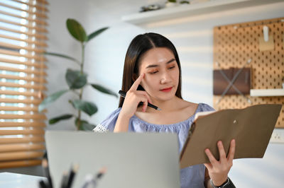 Young woman using laptop while sitting on table