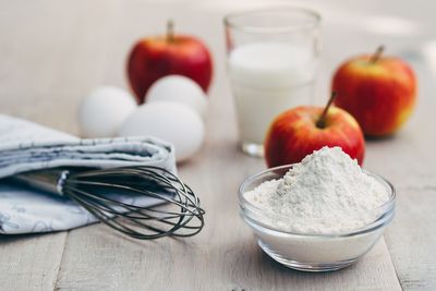 Close-up of wire whisk with apples and flour