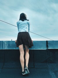 Rear view of woman standing by railing against sea