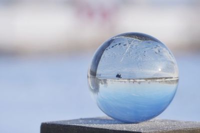 Close-up of crystal ball against blue sky