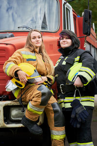 Smiling firefighters standing by fire truck