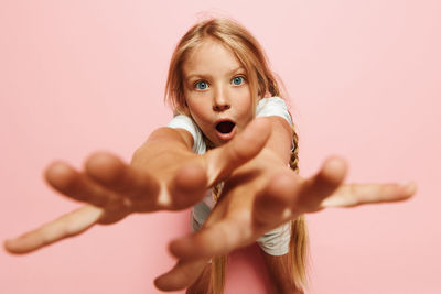 Portrait of smiling young woman gesturing against pink background