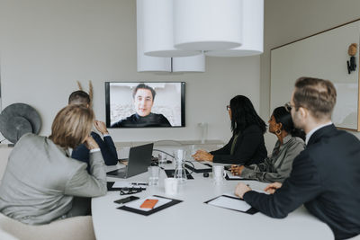 Multiracial colleagues discussing strategy through video conference in board room