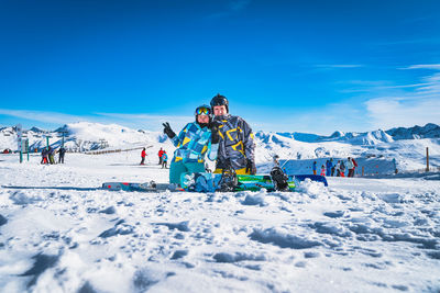 Couple, skier and snowboarder sitting on the snow and looking at camera, pyrenees mountains, andorra