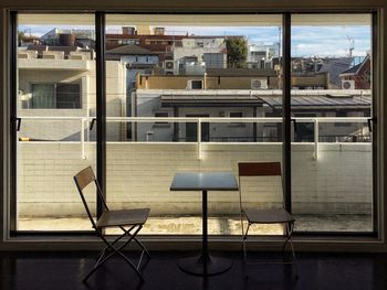 Empty chairs and tables in swimming pool against building