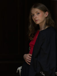 Portrait of young woman standing against wall