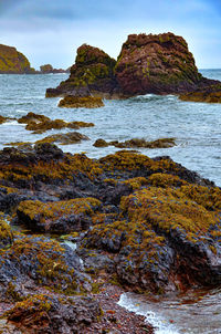 Rock formation on beach against sky