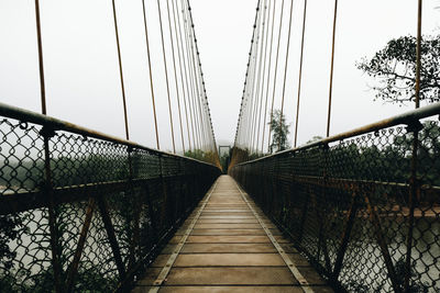 Footbridge over suspension bridge against sky