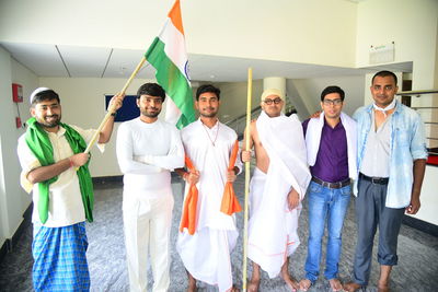Portrait of friends standing with indian flag on floor
