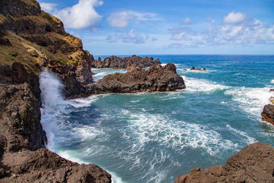 Scenic view of rocks in sea against sky