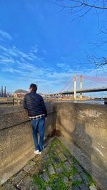 Rear view of man standing on bridge against sky