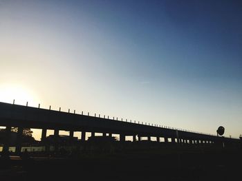 Low angle view of silhouette bridge against clear sky during sunset