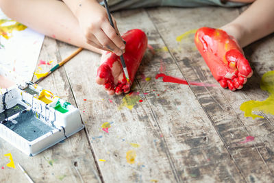 Cropped hand of boy painting barefoot at home