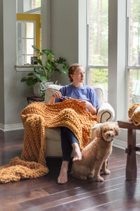 Side view of young woman with dog on floor at home