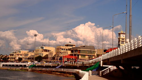 Bridge over river by buildings in city against sky