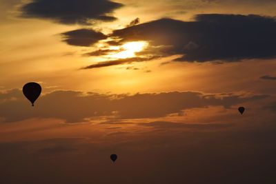 Low angle view of hot air balloons flying against cloudy sky