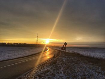 Road by sea against sky during sunset