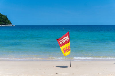 Information sign on beach against sky
