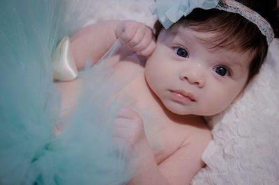 Close-up portrait of cute baby girl lying on bed