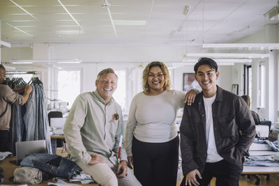 Young female fashion designer with male colleagues at workshop