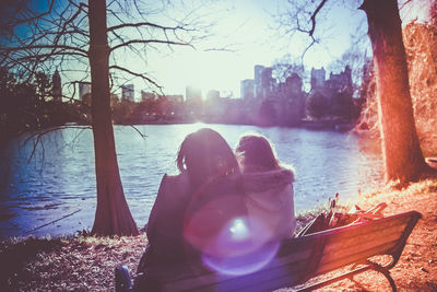 People sitting by river against sky