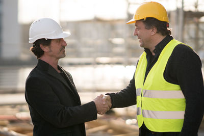 Smiling architects shaking hands at construction site