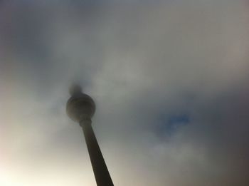 Low angle view of communications tower against cloudy sky