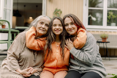 Portrait of smiling girl embracing mother and granddaughter on patio